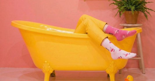 person relaxing in a yellow bathtub wearing mismatched flamingo socks